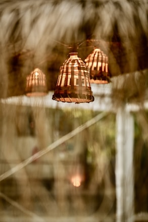 Warm rattan lamps casting soft light over a rustic Mediterranean dining table with olive green accents.