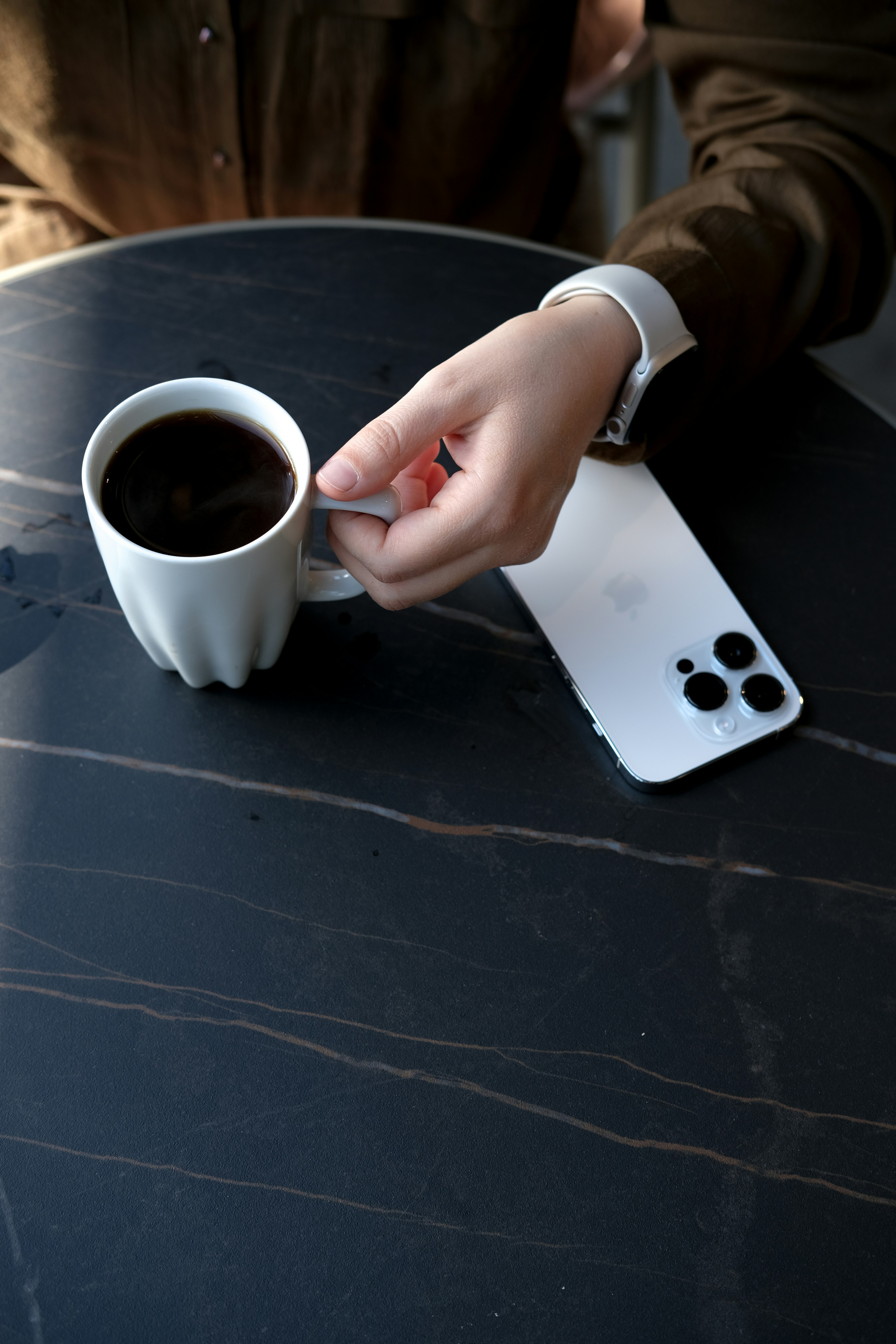 a person holding a phone and a cup of coffee