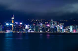 Moody cityscape at night with glowing lights and dark silhouettes.