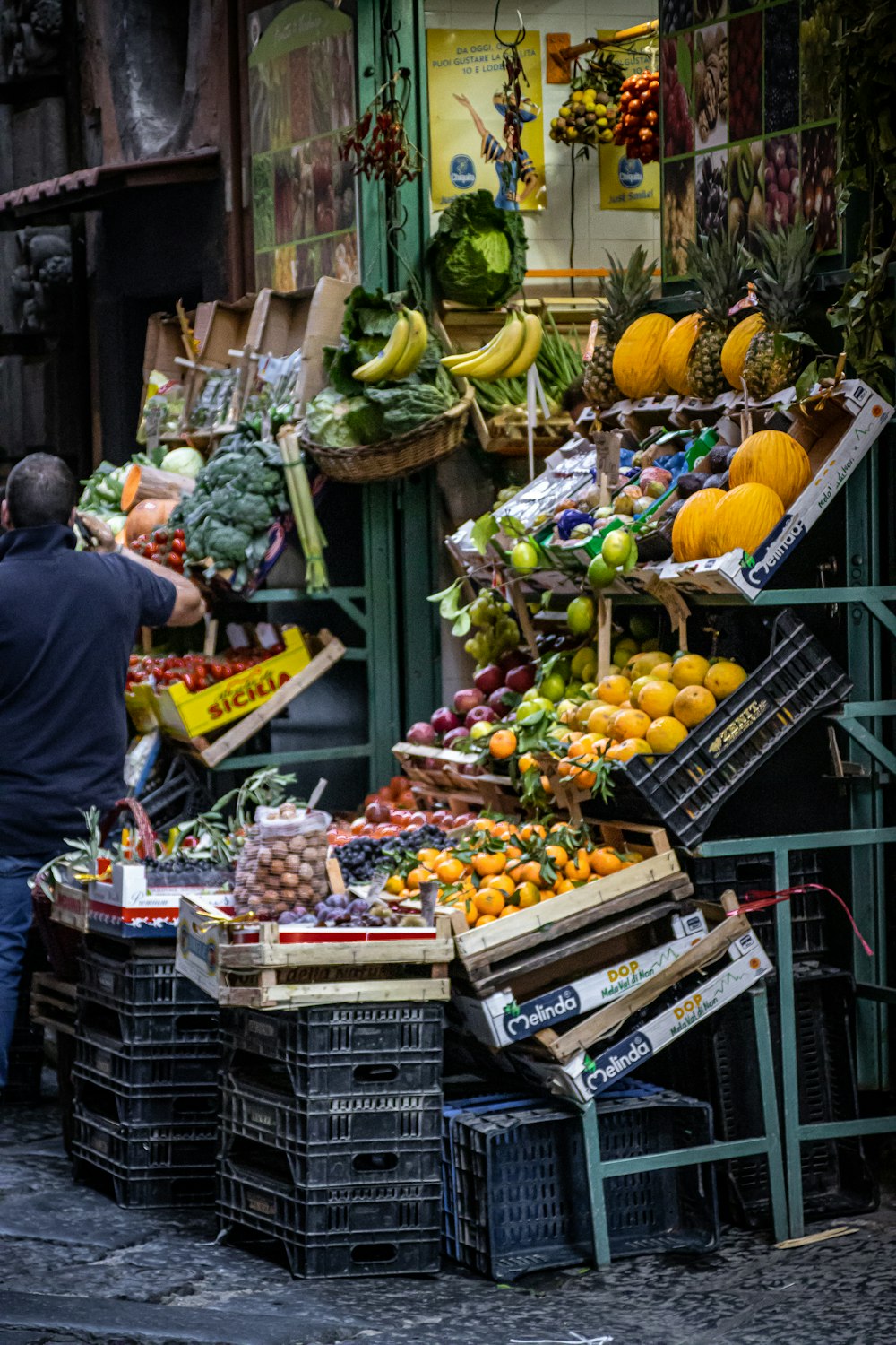 uma pessoa em pé ao lado de uma banca de frutas