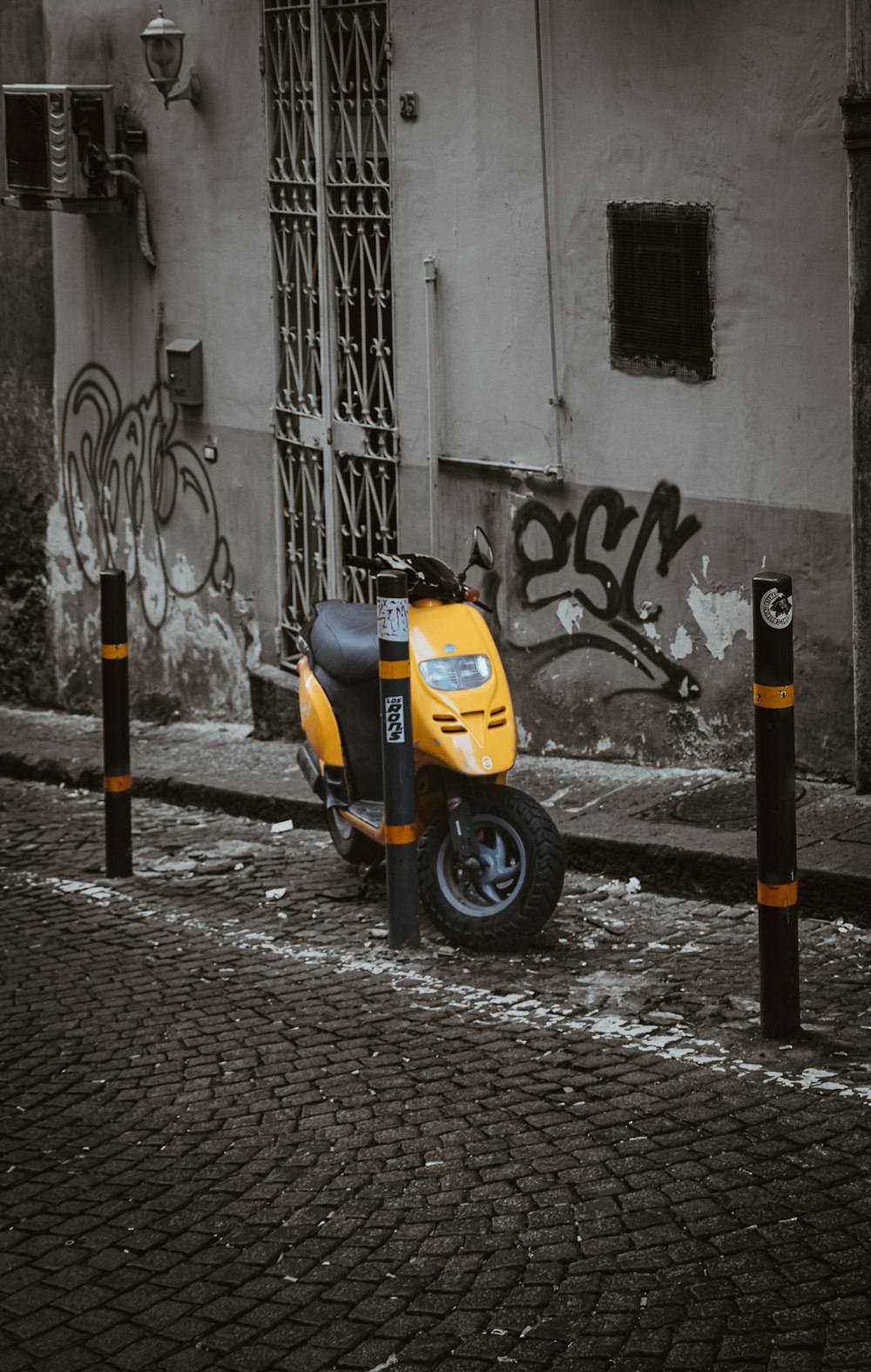 a yellow scooter parked on a brick road