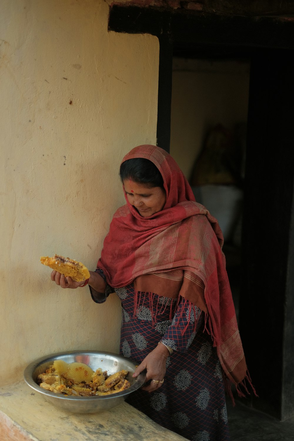 a person in a red head scarf holding a plate of food