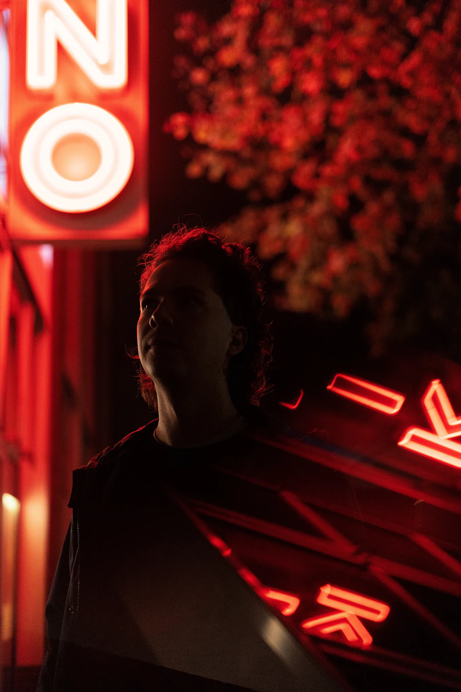 A figure lit from behind by red neon