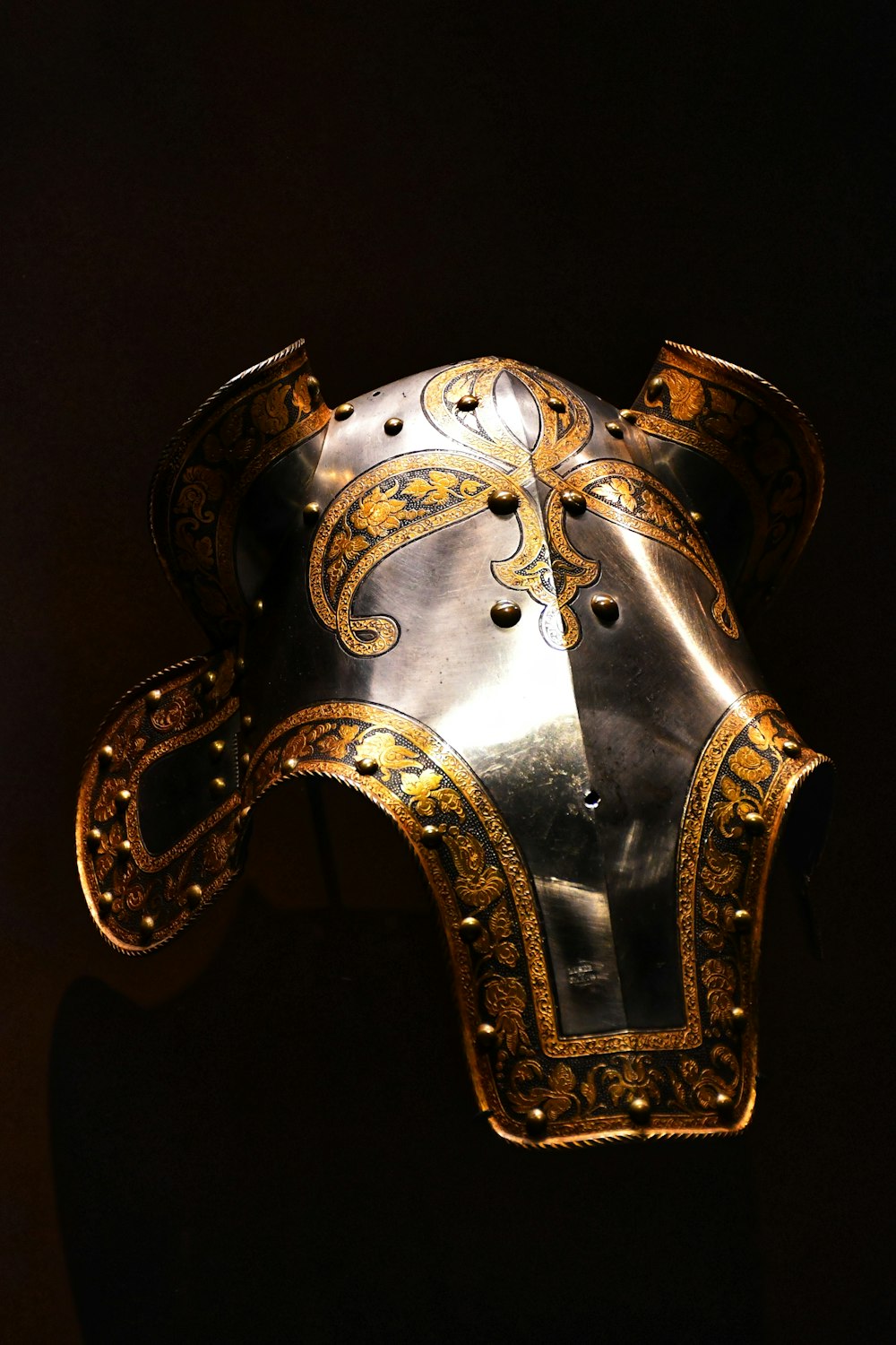 a metal mask with a gold handle
