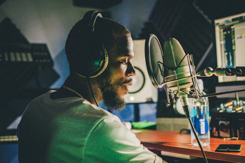 An artist collaborating remotely via video call, headphones on, surrounded by sound equipment.