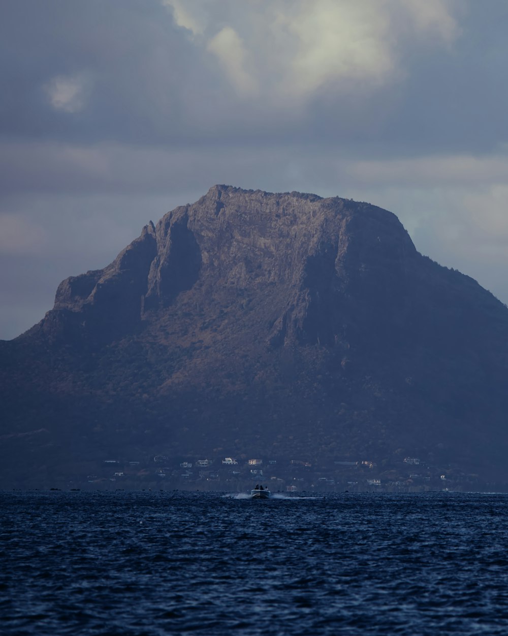 a large mountain next to a body of water