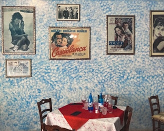 a table with a red tablecloth and chairs with pictures on the wall