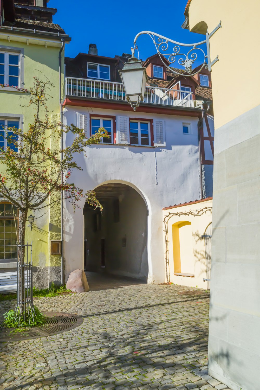 a stone walkway with a stone archway and a building with a satellite dish