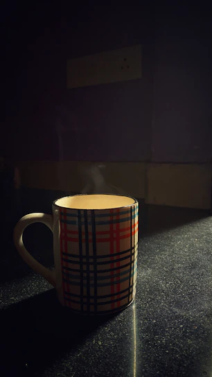A bright hand-thrown stoneware mug with a playful blue glaze and cozy steam rising, sitting on a wooden table.