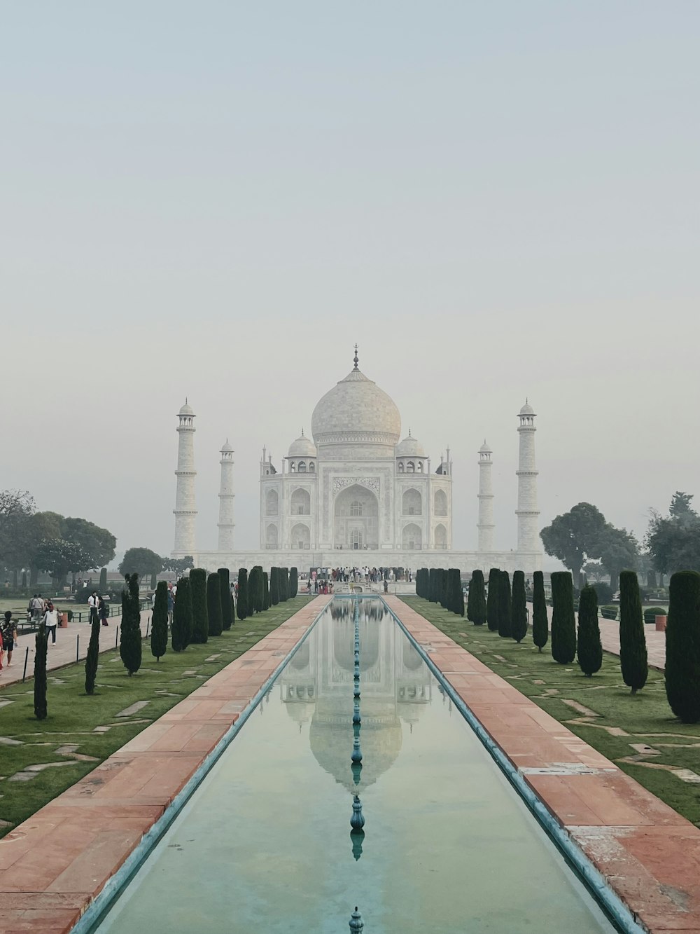 a large white building with a pool in front of it with Taj Mahal in the background