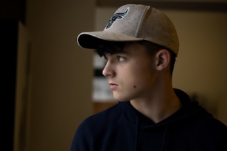 Close-up of a nameless faceless cap with embroidered logo, worn by a young person in an urban setting.
