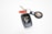 A set of keys is prominently displayed, featuring a black car key with a Land Cruiser logo and a metallic ring. Attached to the ring is a red and black keychain that holds a small circular device with what appears to be an Apple logo.