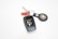 A set of keys is prominently displayed, featuring a black car key with a Land Cruiser logo and a metallic ring. Attached to the ring is a red and black keychain that holds a small circular device with what appears to be an Apple logo.