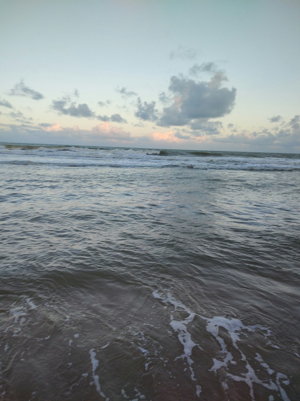 a body of water with waves and clouds in the sky