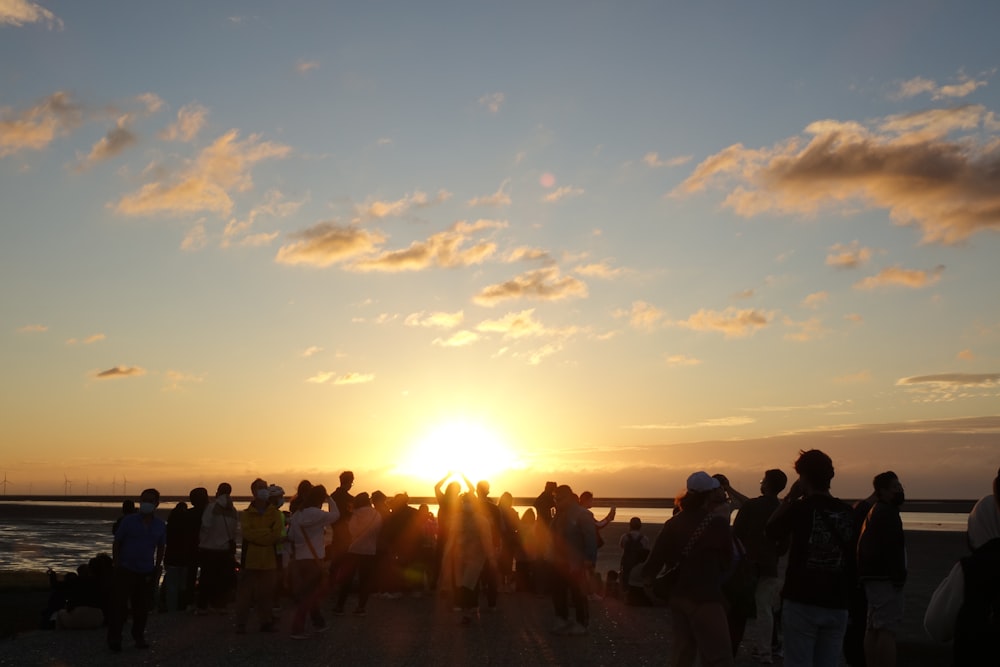 a group of people standing on a beach at sunset