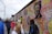 A diverse group of people admiring colorful street art murals outdoors.