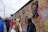 A diverse group of people admiring colorful street art murals outdoors.
