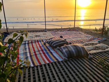 a deck with a blanket and a beach in the background