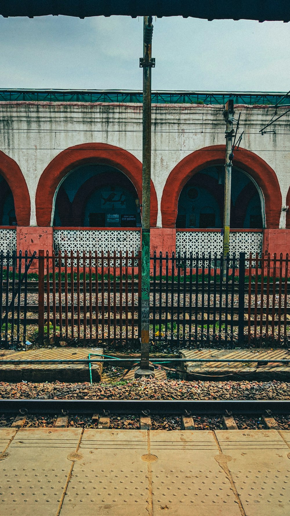 a train track with a fence and a building in the background