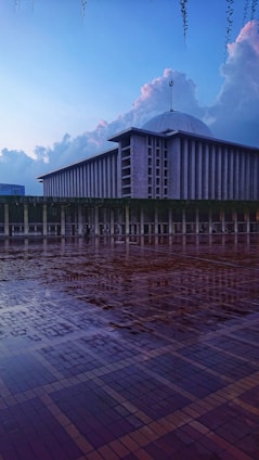 A serene mosque courtyard bathed in soft morning light with green and blue accents reflecting tranquility.