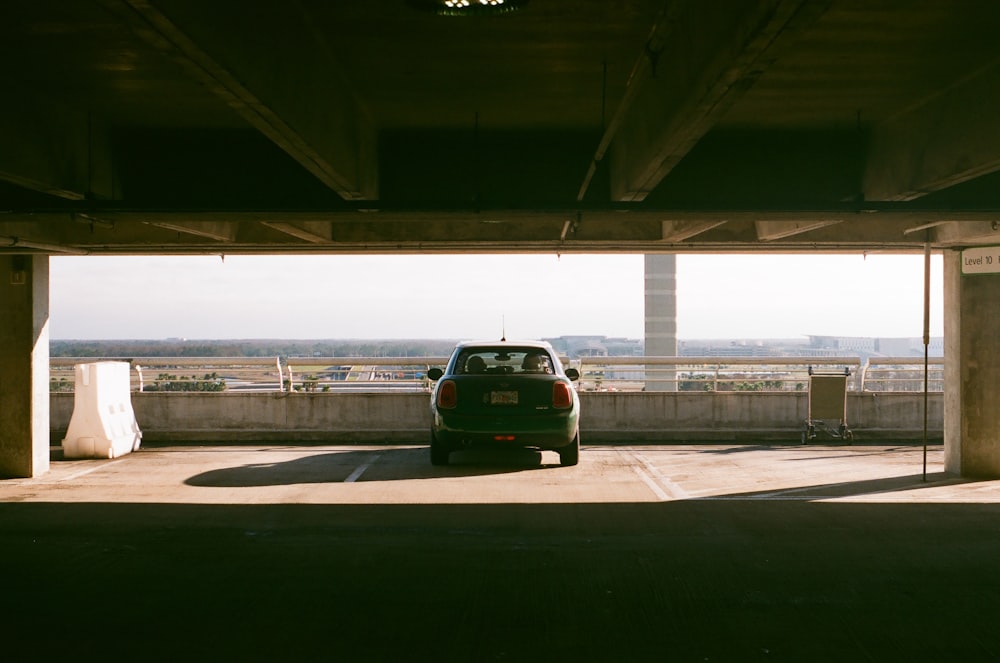 a green car parked under a bridge