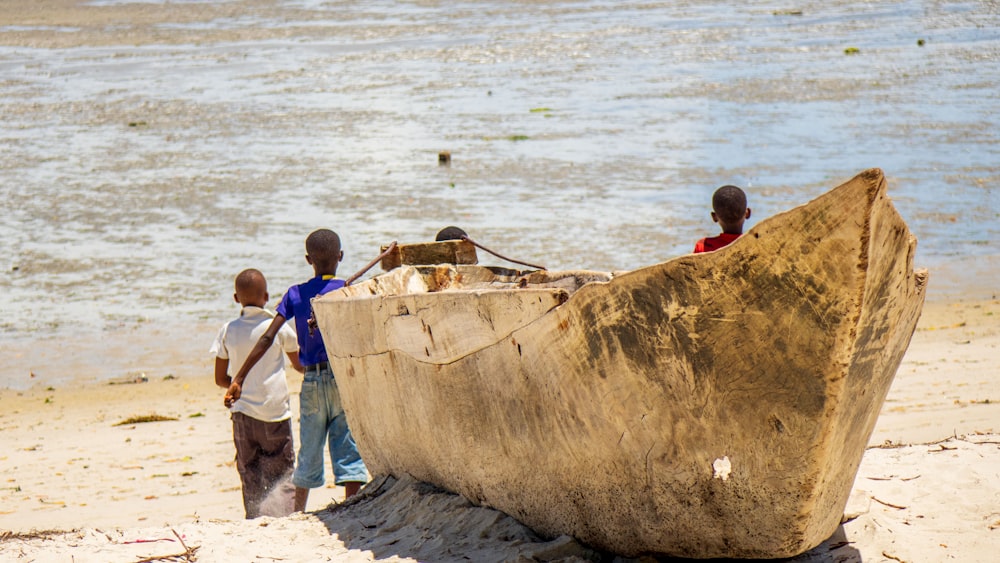 a group of kids standing next to a large tank on a beach