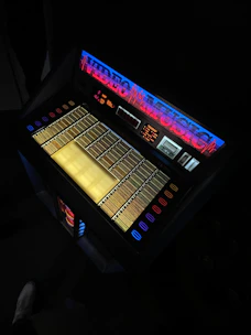 A modern jukebox glowing with colorful lights in a cozy bar setting.