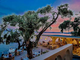Cozy seaside restaurant terrace with navy and white decor during sunset.