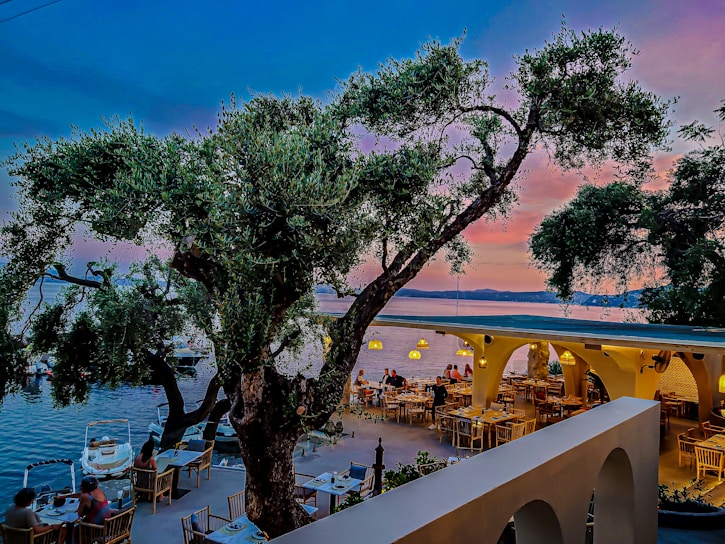 A vibrant seaside restaurant terrace at sunset with diners enjoying local dishes.