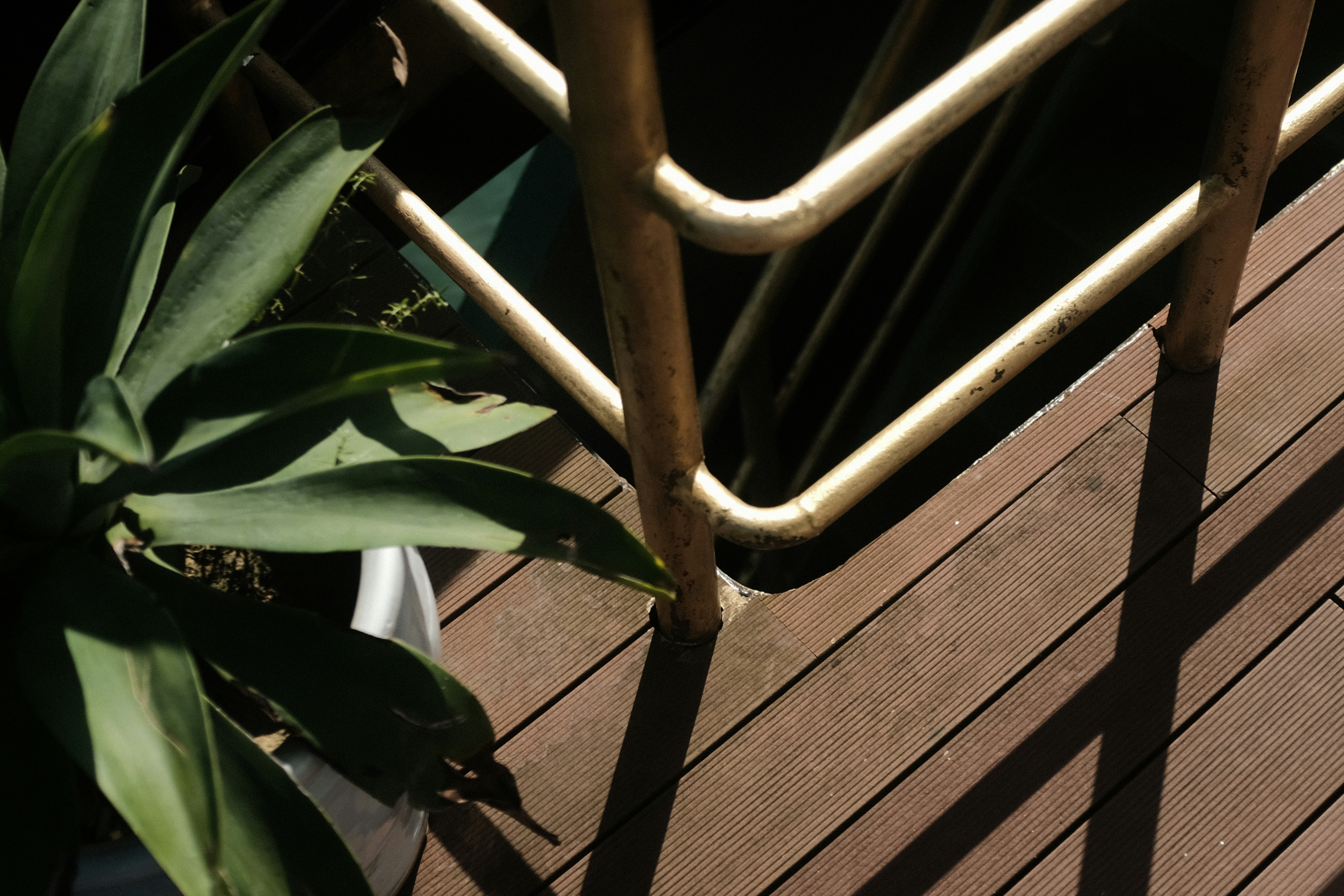 Luxury composite deck renovation with dark wood tones, glass railings, built-in planters, and evening ambient lighting creating dramatic shadows