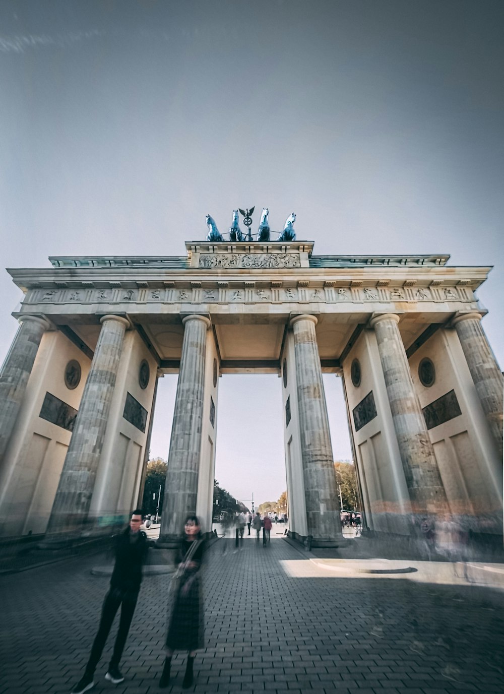 a couple of people standing in front of a building with columns and statues