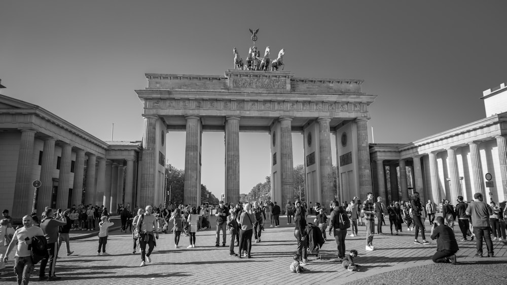 a large group of people walking in front of Brandenburg Gate with columns