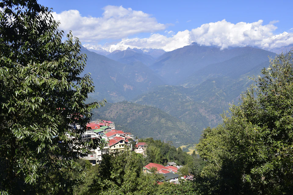 Red roofed hotels of Pelling standing on their forested ridge above a deep valley in West Sikkim