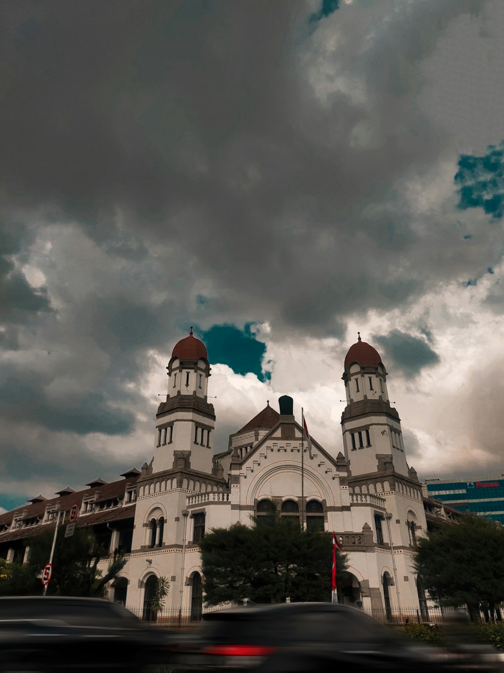 a large white building with a red dome and a cloudy sky