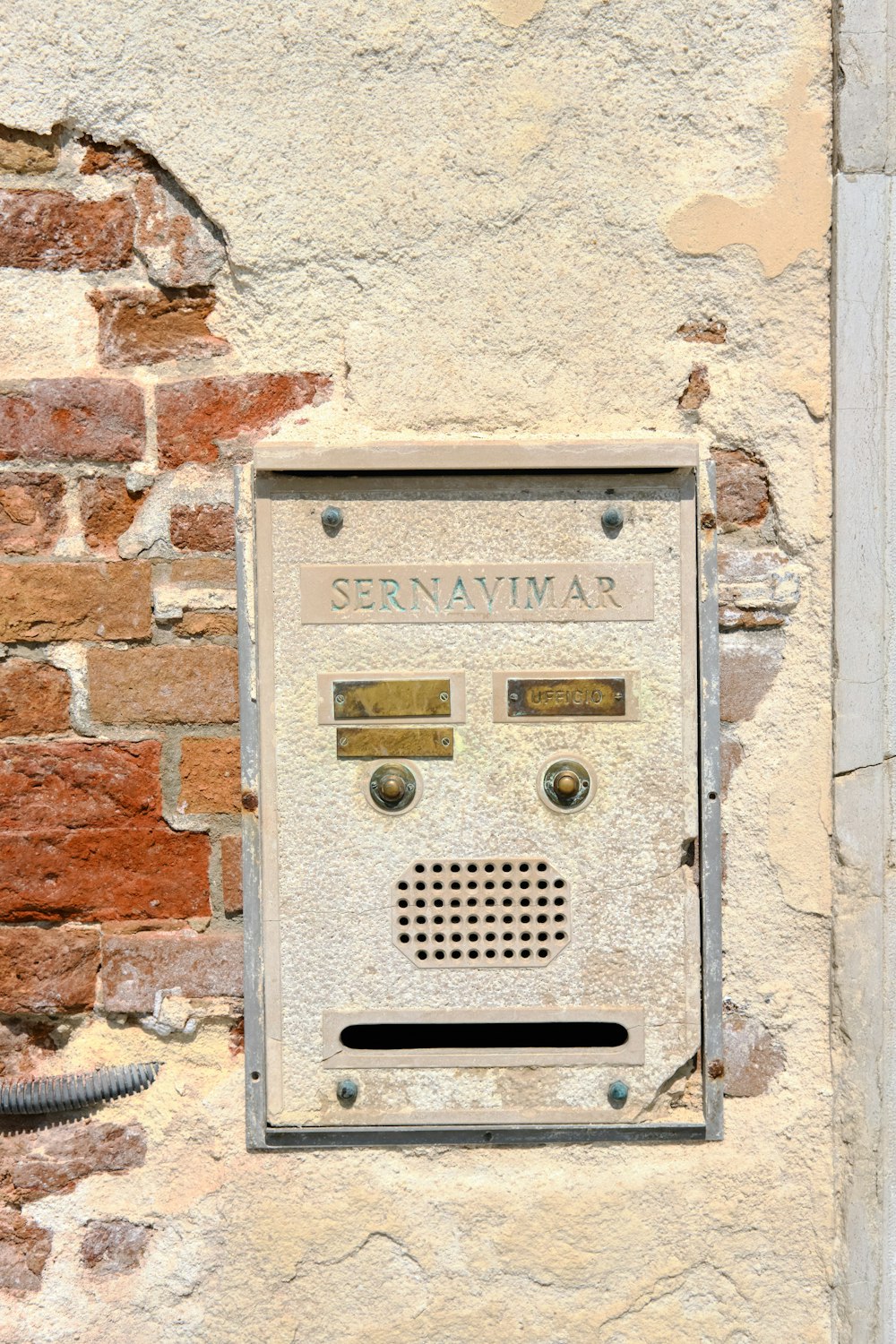 a rectangular metal box on a brick wall