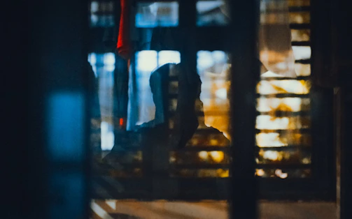 Shadowy figure behind a cracked window in dim light