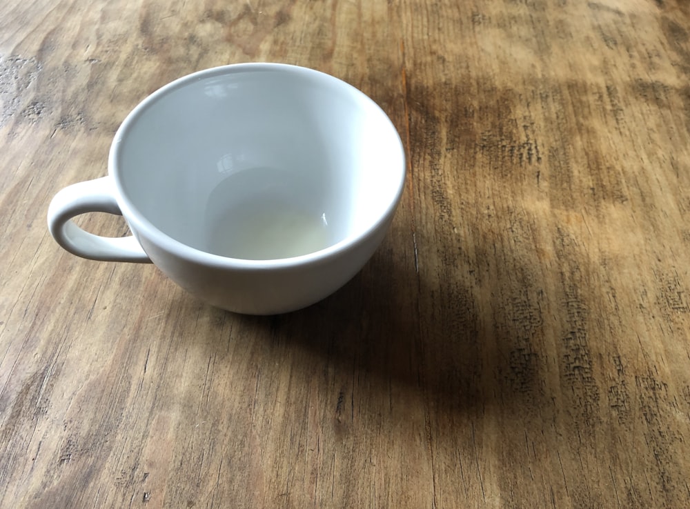 a white cup on a wooden surface