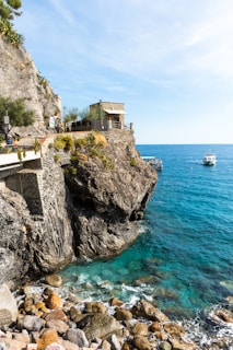 a rocky cliff with a building on it by the water