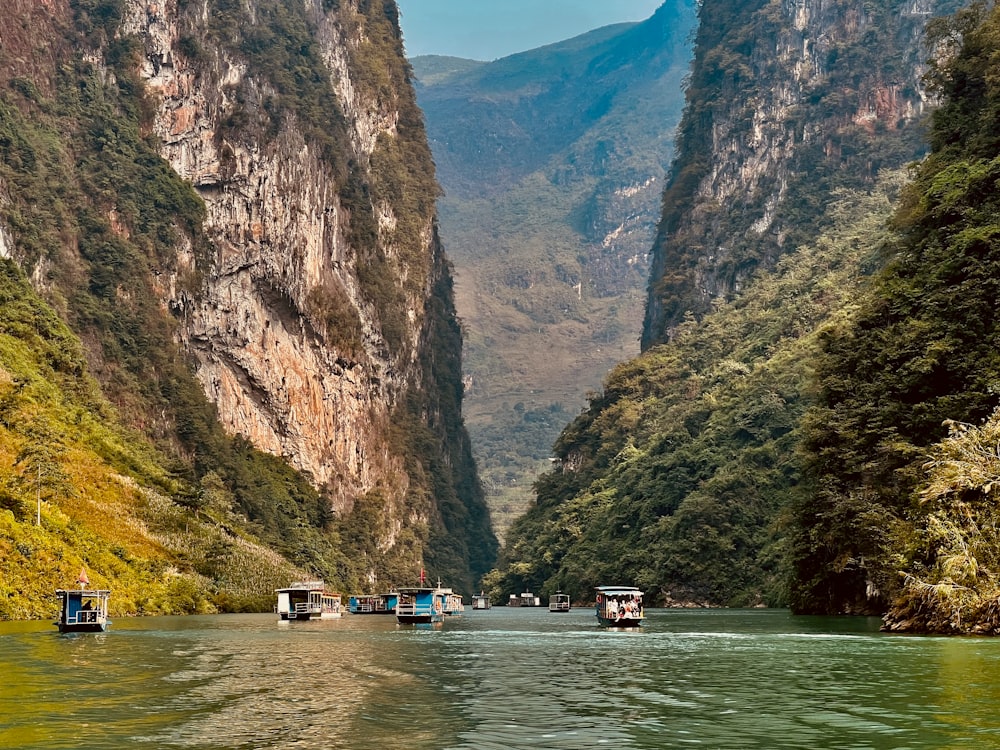 a group of boats on a river between mountains