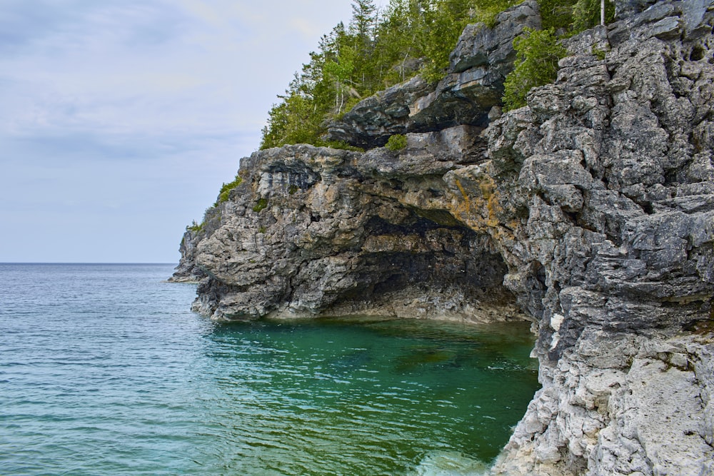 un acantilado con un cuerpo de agua debajo con el Parque Nacional Bruce Peninsula al fondo