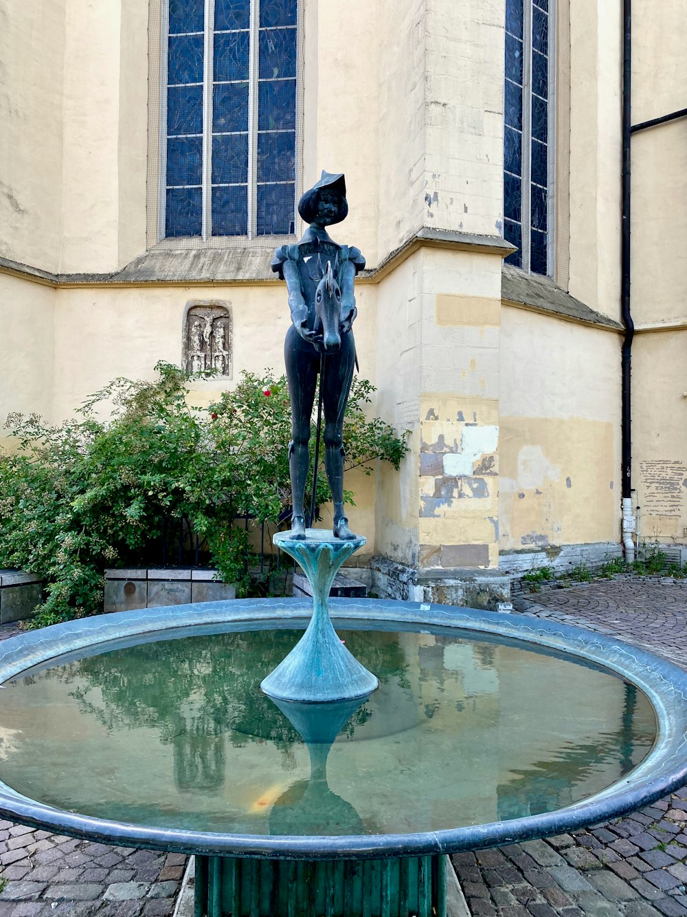 une statue d’une personne dans une fontaine devant un bâtiment