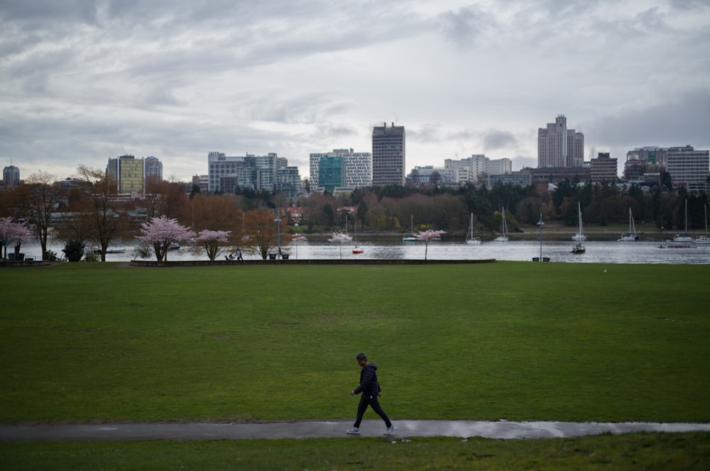 a person running on a grass field with a city in the background