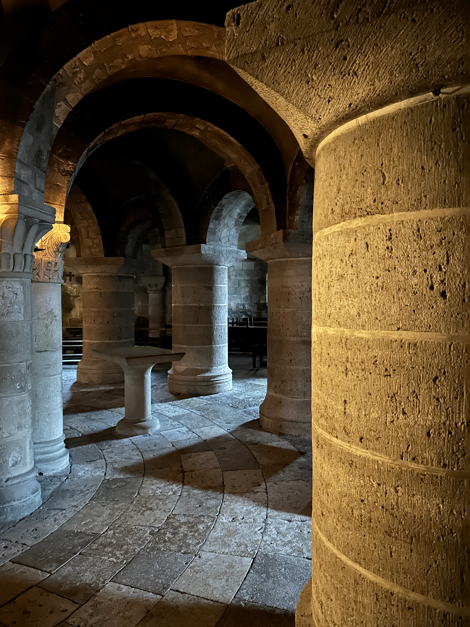 A stone walkway between heavy columns in warm sandstone.