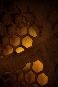A modern hexagonal pattern background with subtle honeycomb shapes in warm yellow and gray tones.