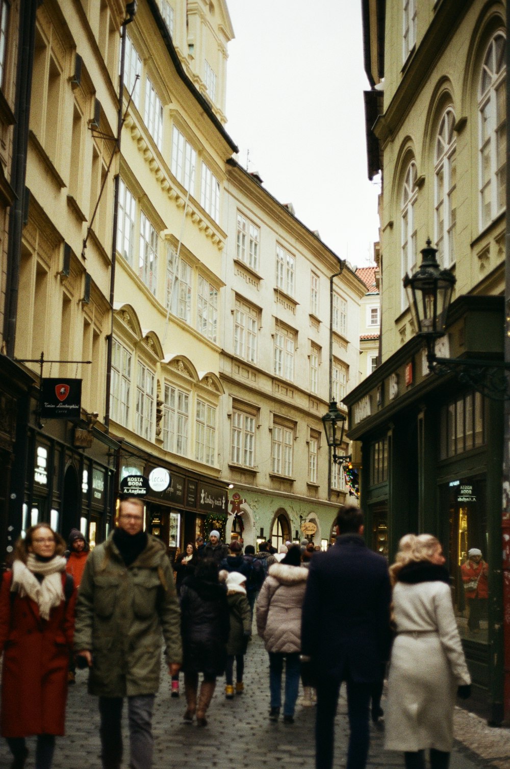 a group of people walking down a street between buildings