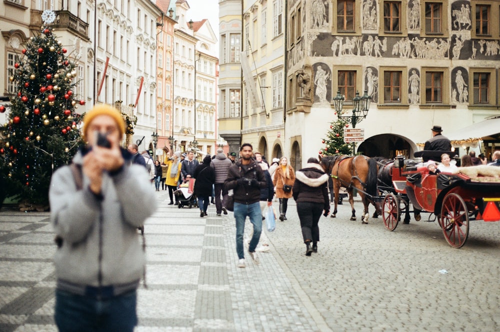 a person taking a picture of a parade with a horse and carriage
