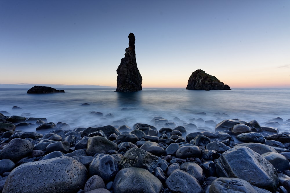 une plage rocheuse avec un gros rocher dans l’eau