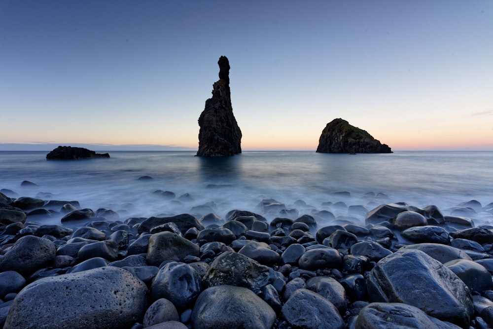 a rocky beach with a large rock in the water