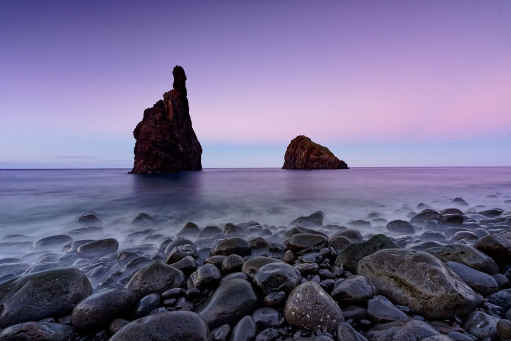 a rocky beach with a large rock in the distance