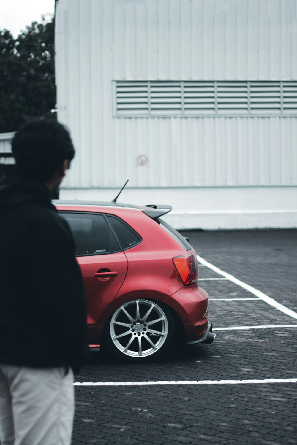 um homem de pé ao lado de um carro vermelho
